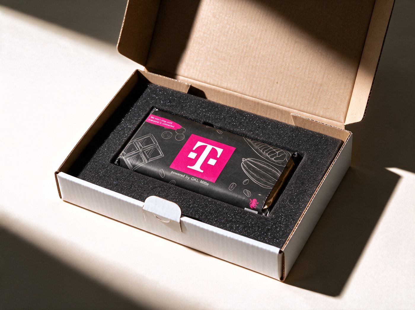 Individuelle Versandverpackung: Schokoladentafel mit Banderole im Corporate Design, fixiert in der Schaumstoff-Einlage eines Versandkartons